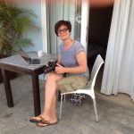 Karin Hirsch-Gerdes sitzt mit Laptop und Kamera auf der Terasse ihres Hotelzimmers