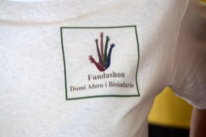 Logo Fundashon Domi Abou i Bisindario auf Curaçao mit vielen Armen die sich in die Luft strecken