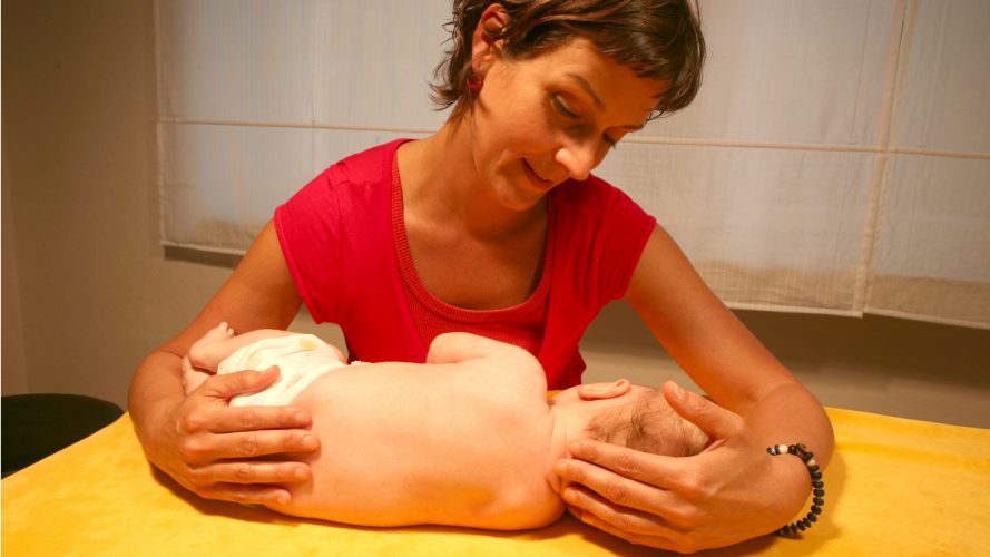 Die Dozenting Kathi Exner-Panne arbeitet mit einen Säugling auf einer Behandlungsbank
