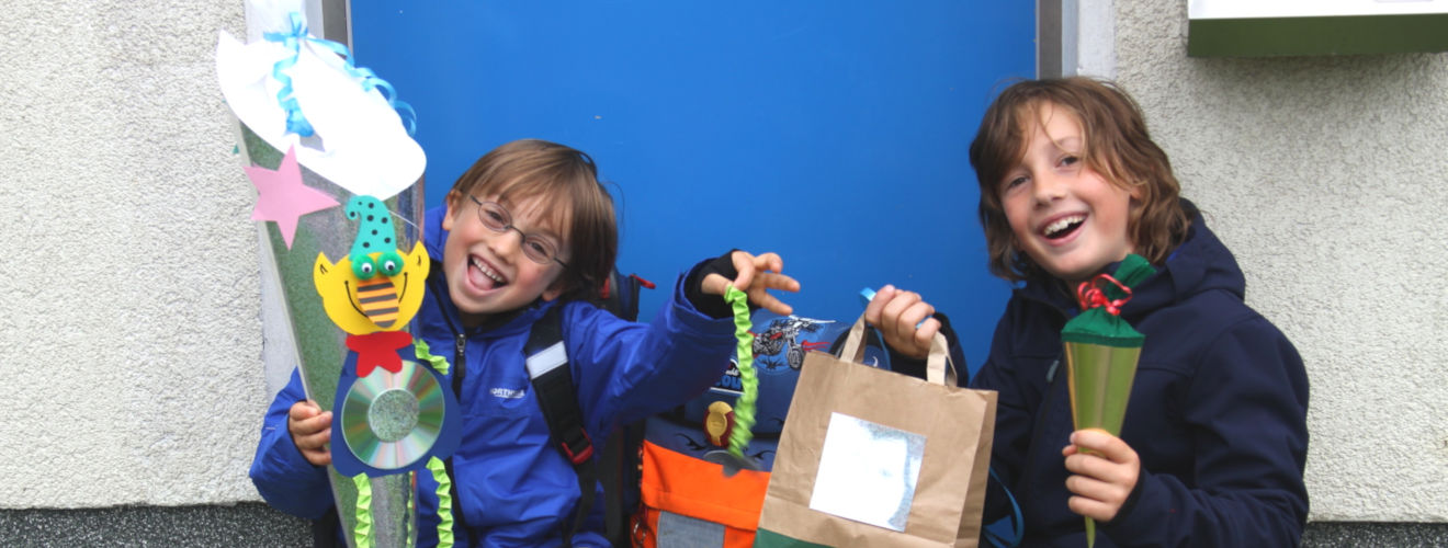 Moritz (re.) und Max (li.) sitzen vor der blauen Haustür mit Schultüten